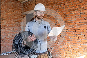 A worker at a construction site holds an electrical cable