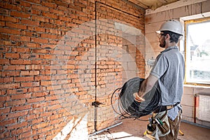 A worker at a construction site holds an electrical cable