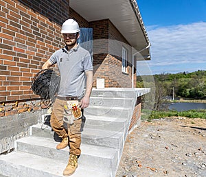 A worker at a construction site holds an electrical cable