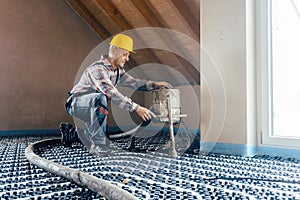 Worker on construction site installing pipes for underfloor heating