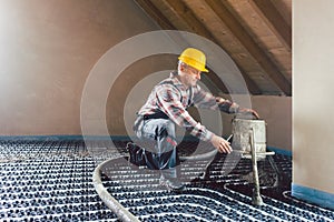 Worker on construction site installing pipes for underfloor heating