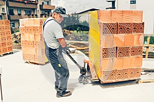 Worker on construction site, moving bricks and working on building walls