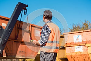 Worker on construction site unloading container for waste from t