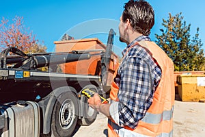 Worker on construction site unloading container for waste from truck