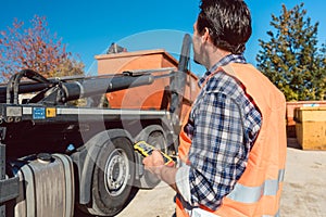 Worker on construction site unloading container for waste from truck
