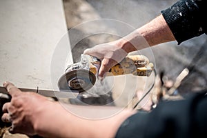 Worker at construction using grinder for cutting slate