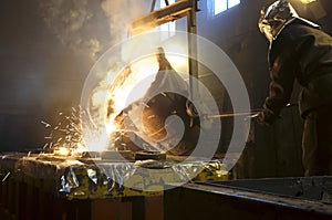 Worker controlling metal melting in furnaces. Worker operates at the metallurgical plant. The liquid metal is poured