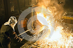 Worker controlling metal melting in furnaces. Workers operates at the metallurgical plant. The liquid metal is poured