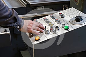 The worker controls the control panel for switching modes of grinding on a cylindrical grinding machine