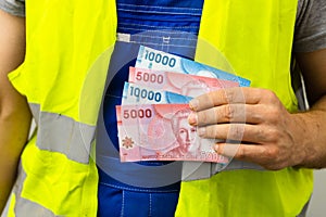 Worker counting his earnings, Chile money, Concept of wages and labor costs in industry