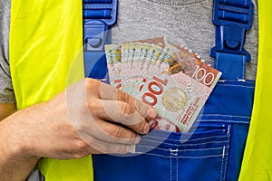 Worker counting his earnings, New Zealand  money, Concept of wages and labor costs in industry