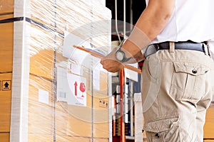 Worker courier holding clipboard writing on checklist for delivering shipment pallet goods