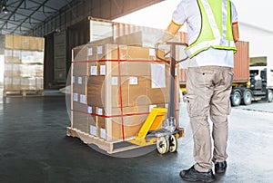 Worker Courier Using Hand Pallet Jack Unloading Package Boxes into Cargo Container. Delivery service. Truck Loading Dock Warehouse