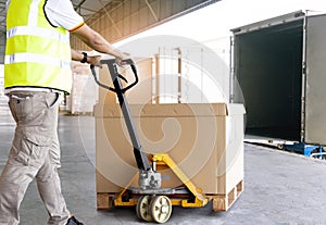 Worker courier working with hand pallet truck loading shipment goods to a truck.