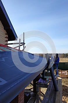 The worker covers the roof with thermal insulation material, waterproof film