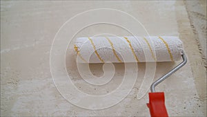 A worker covers the wall with plaster. Worker and roller. Male hand painting wall with paint roller. Painting apartment,