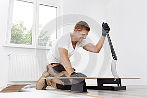 Worker cut wooden batten for laminate floor, floating wood tile