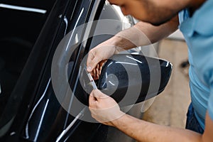 Worker cuts film, car tinting installation process