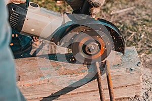 The worker cuts the metal with an angle grinder, the work is carried out on the street