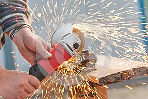 Worker cuts metal electric saw.