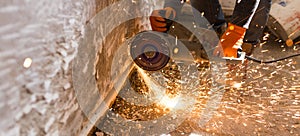 Worker cuts a metal pipe with sparks