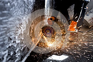 Worker cuts a metal pipe with sparks