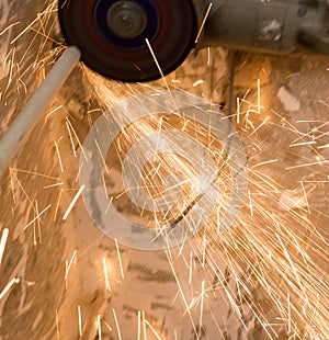 Worker cuts a metal pipe with sparks