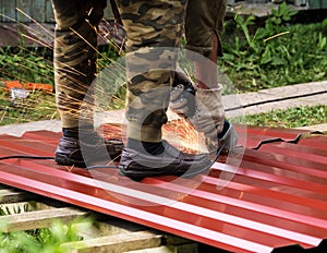 The worker cuts a metal sheet with angle grinder