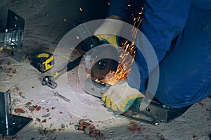 The worker cuts off the metal with a grinding machine. Workflow at the construction site