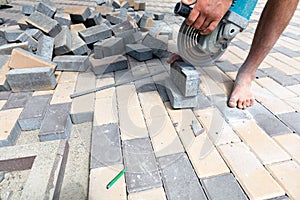 A worker cuts paving slabs with a grinder for subsequent laying