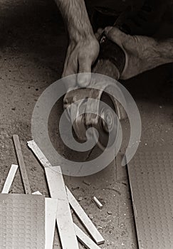 Worker cuts tiles with the angle grinder