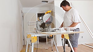 Worker cuts wood baseboard on the power miter saw