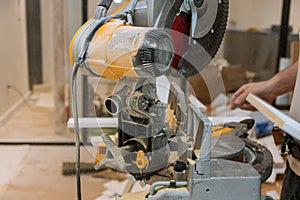 Worker cuts the wood moldings baseboard on the miter saw