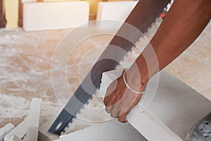 Worker cutting bricks with crosscut saw.