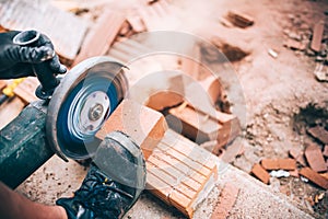 worker cutting through bricks. Professional brickmason using grinder at building houses