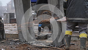 Worker cutting concrete piles with cutter or circular saw on construction site