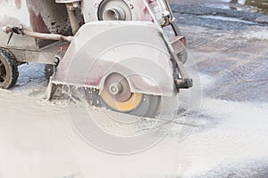 Worker cutting concrete road with diamond saw blade machine