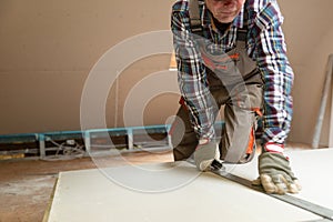 Worker cutting drywall plasterboard with construction knife. Attic renovation