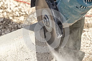 Worker with a cutting flex cuts a concrete curb