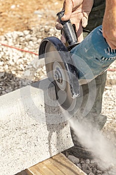 Worker with a cutting flex cuts a concrete curb