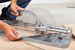 Worker cutting floor tiles with manual cutter