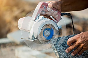 Worker cutting granite stone with an diamond electric saw blade and use water to prevent dust and heat