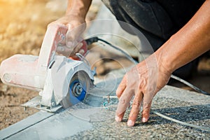 Worker cutting granite stone with an diamond electric saw blade and use water to prevent dust and heat