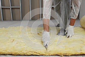 Worker cutting insulation material indoors, closeup. Space for text