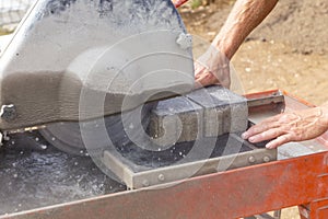 Worker with a cutting machine cuts a concrete curb