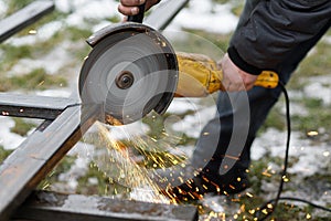 Worker cutting metal with angle grinder machine for welding iron. Close up of circular grinder disc and electric sparks. Workers