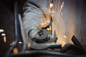 Worker cutting metal with grinder. Sparks flying while grinding.