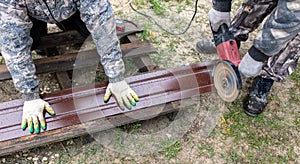 A worker is cutting metal to install a fence