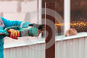 A worker is cutting metal to install a fence