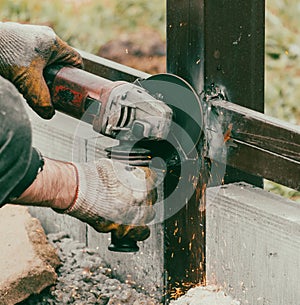 A worker is cutting metal to install a fence